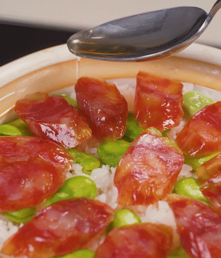 大米出現(xiàn)小孔時(shí)開蓋放香腸，往鍋邊淋入少許油，再燜煮8~10分鐘左右。