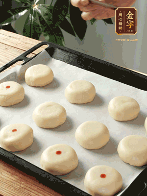 收口向下放在案板上，輕輕將月餅坯按扁，用筷子點紅點做裝飾