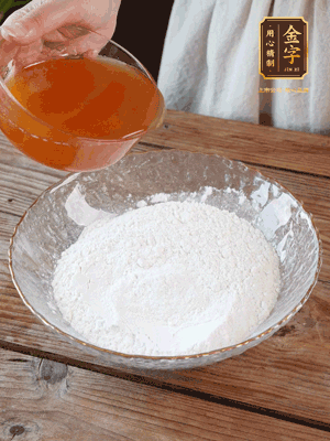 轉(zhuǎn)化糖漿、枧水、花生油攪拌均勻，加入面粉混合，醒發(fā)2小時(shí)。捏成23g一個(gè)的小球